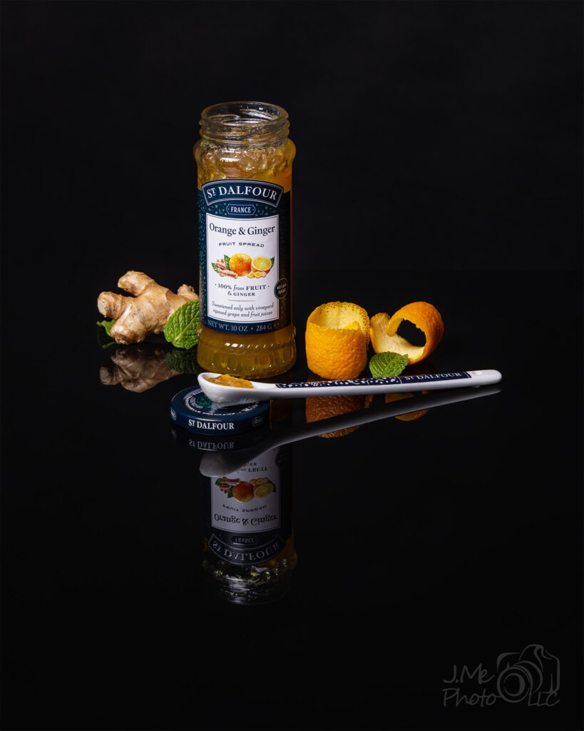Orange and Ginger Jam Image showing a jar of St Dalfour Orange and Ginger Jam, decorated with some ginger on the left and an orange peel on the right with a spoon containing some of the jam.